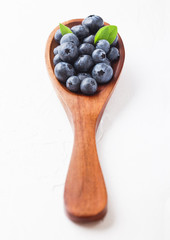 Fresh raw organic blueberries with leaf on wooden spoon on white background. Food concept.