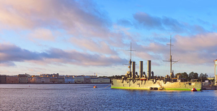 Revolutionary ship-museum Cruiser Aurora at the confluence of the Bolshaya Nevka and Neva rivers, St Petersburg, Russia. Kutuzov Embankment. Morning dawn, sunrise, aurora, panoramic view