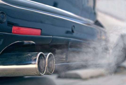 Close up of smoky dual exhaust pipes from a starting diesel car.