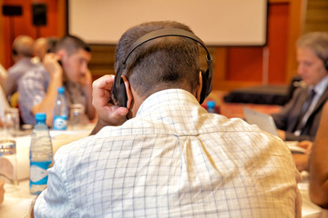 Unrecognizable people using in ear headphones for translation during event Unrecognizable business people using headphones for translation during event