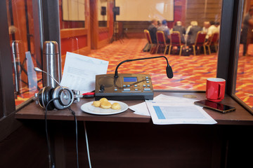 Translator room . translators cubicle . interpreting - Microphone and switchboard in an simultaneous interpreter booth . Soft focus of wireless Conference microphones and notebook in a meeting room.