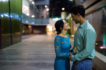 Young Hispanic couple exploring the city streets at night togeth