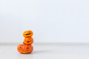 Jack-o-lantern carved pumpkin on light wall background with copy space, autumn and halloween home...