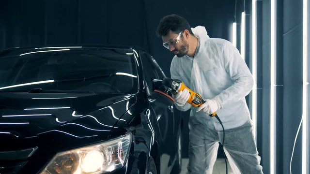 Male mechanic buffing a car, close up.