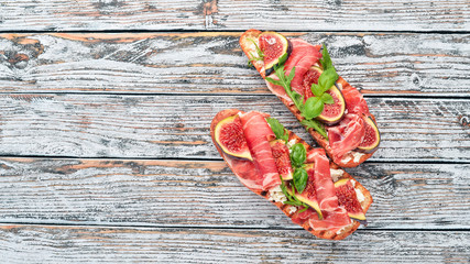 Bruschetta with prosciutto, fresh figs and cheese. On the old background. Healthy food. Free space...