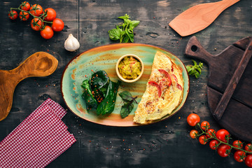 Omelet with spinach and tomatoes. Breakfast. On a wooden background. Free copy space. Top view.