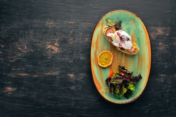 Sandwich with avocado, bacon and poached egg. Top view. Free space for your text. On a wooden background.