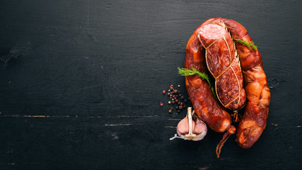 Smoked sausage with lard. On a black wooden background. Top view. Free space for your text.