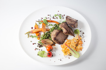 Baked meat with cheese, carrot, onion, green and tomatoes on white plate