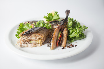Baked mackerel with green salad and lemon on white plate