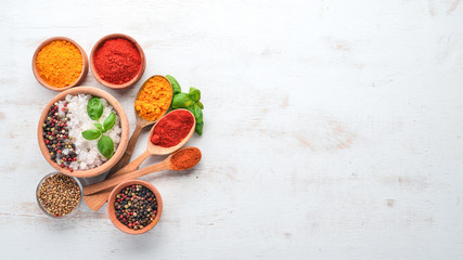A set of Spices and herbs on a white wooden table. Basil, pepper, saffron, spices. Indian...