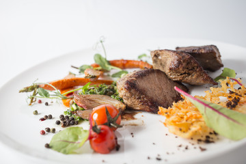 Baked meat with cheese, carrot, onion, green and tomatoes on white plate