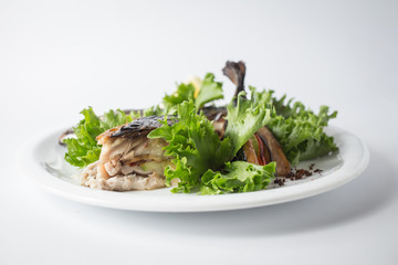 Baked mackerel with green salad and lemon on white plate