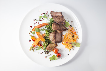 Baked meat with cheese, carrot, onion, green and tomatoes on white plate
