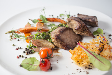 Baked meat with cheese, carrot, onion, green and tomatoes on white plate