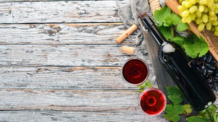 A bottle of red wine on a white wooden background. Grape. Free space for text. Top view.