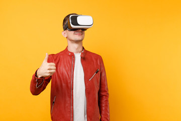 Portrait vogue handsome young man in red leather jacket, t-shirt looking in headset standing isolated on bright trending yellow background. People sincere emotions lifestyle concept. Advertising area.