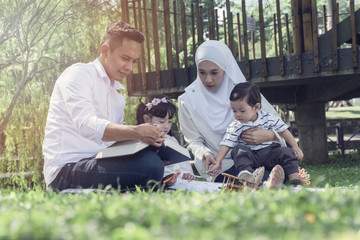 Education and family concept,happy parents with children read a book in the park