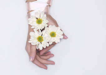 Fashion art hand woman in summer time and flowers on her hand with bright contrasting makeup. Creative beauty photo hand girls sitting at table on contrasting background with colored shadows. Skincare