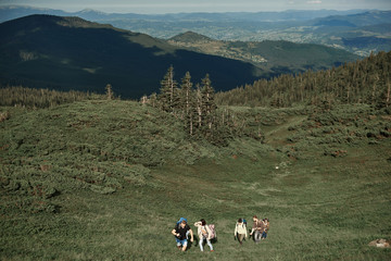 Top view of two men and three women walking up mount. They backpacking together in beautiful highland