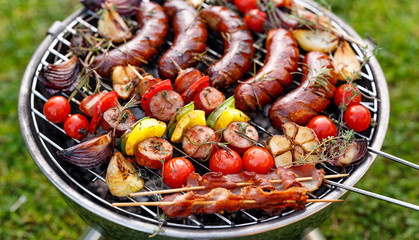 Grilled food. Various grilled products: Grilled sausages, meat and vegetable skewers, bacon and vegetables on the grill plate, outside. Barbecue, bbq