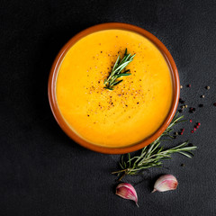 Pumpkin and carrot  Cream soup with garlic on a black board  background. Autumn cream-soup in country style. Top view. Copy space.