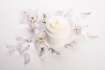 Cute flowers and petals and a jar of natural body cream isolated on white background