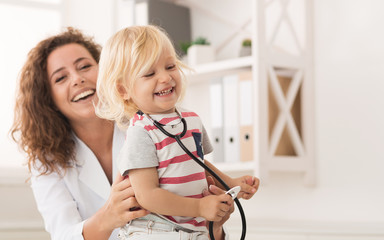 Little boy laughing while female doctor examining child
