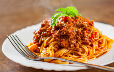 Traditional pasta spaghetti bolognese in white plate on wooden table background