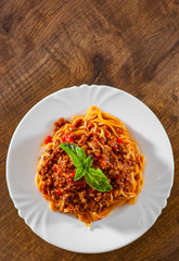Traditional pasta spaghetti bolognese in white plate on wooden table background