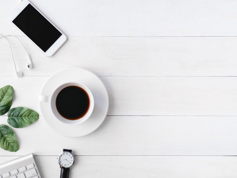 top view of office desk workspace with coffee cup, notebook, plastic plant, smartphone and keyboard on white background, graphic designer, Creative Designer concept.