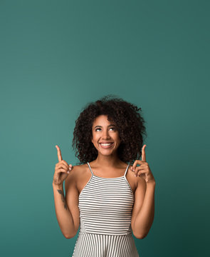 Smiling Woman Pointing Fingers Up Over Blue Background