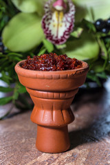 Hookah in a clay bowl for Smoking hookah on the background of greenery and orchids