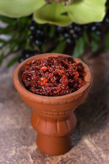 Hookah in a clay bowl for Smoking hookah on the background of greenery and orchids