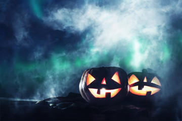Halloween holiday concept. Pumpkins over wooden table at night scary, haunted and misty forest.
