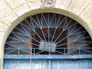 facade of an ochre pastel with a blue metal door with iron cast decorations