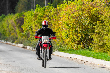 A man on a cross-country motorcycle riding along an asphalt road