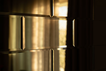 The surface of the mirror tiles. Wall of mirrored tiles with edges. Interior design with sunset...