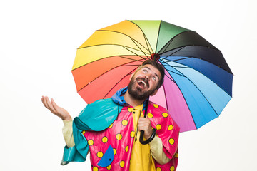 Brutal bearded man with rainbow-colored umbrella isolated on white background. Rain weather. Cloud...