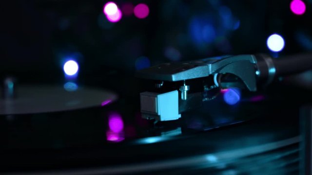 Vinyl record player. Stylus drops. Night cold neon lights background.