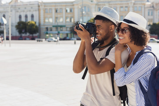 African-american tourist couple taking photos on camera on street