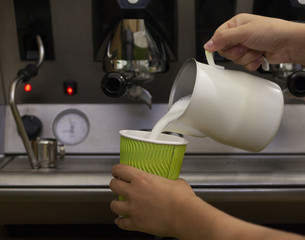 barista making hot coffee with milk