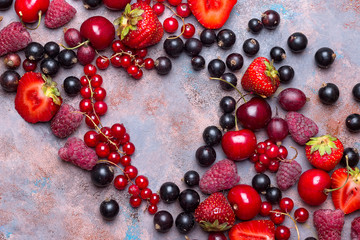 Heart shape assorted berry fruits on stone background. Flat lay
