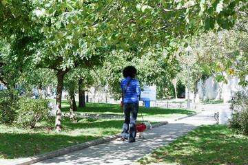 Woman with a poodle hair style walking a poodle dog