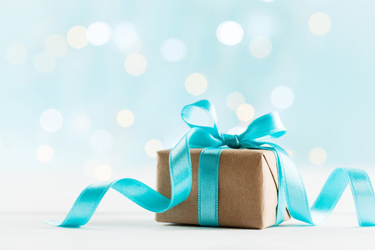 Christmas gift or present box against turquoise bokeh background. Holiday greeting card.