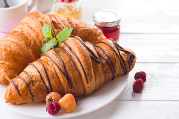 Fresh tasty croissants with berries on white wooden background