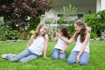 mother and her daughters sitting on the grass