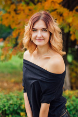 Charming woman in a black dress in the autumn park