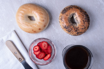 Breakfast of Coffee, Bagels, Cream Cheese, Blackberries and Strawberries on a Marble Surface.