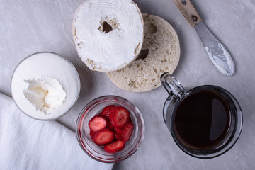 Fototapeta na wymiar Breakfast of Coffee, Bagels, Cream Cheese, Blackberries and Strawberries on a Marble Surface.